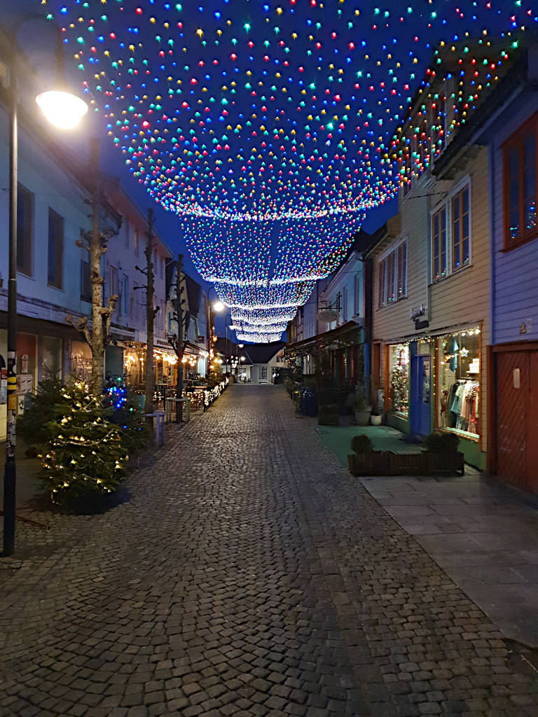 Wellenförmige bunte Lichterkette über der Straße Fargegata in Stavanger.