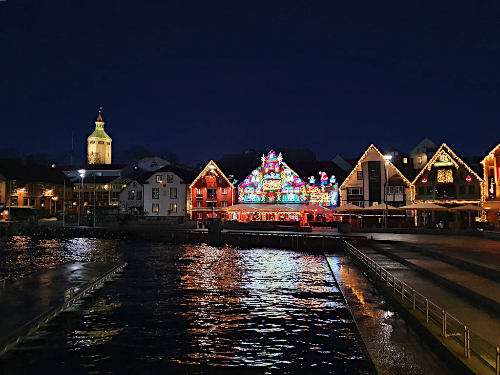 Blick auf weihnachtlich geschmückte Hausfassaden am Skagenkaien, Stavanger, während der Dämmerung.