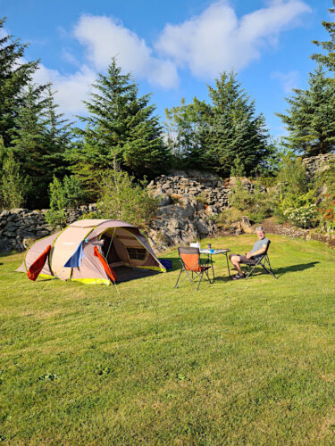 Offenes Zelt auf Campingplatz mit Tisch und Stühlen