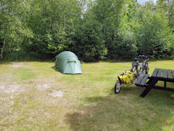 Kleines grünes Zelt auf einem Campingplatz. Tandem mit Anhänger.